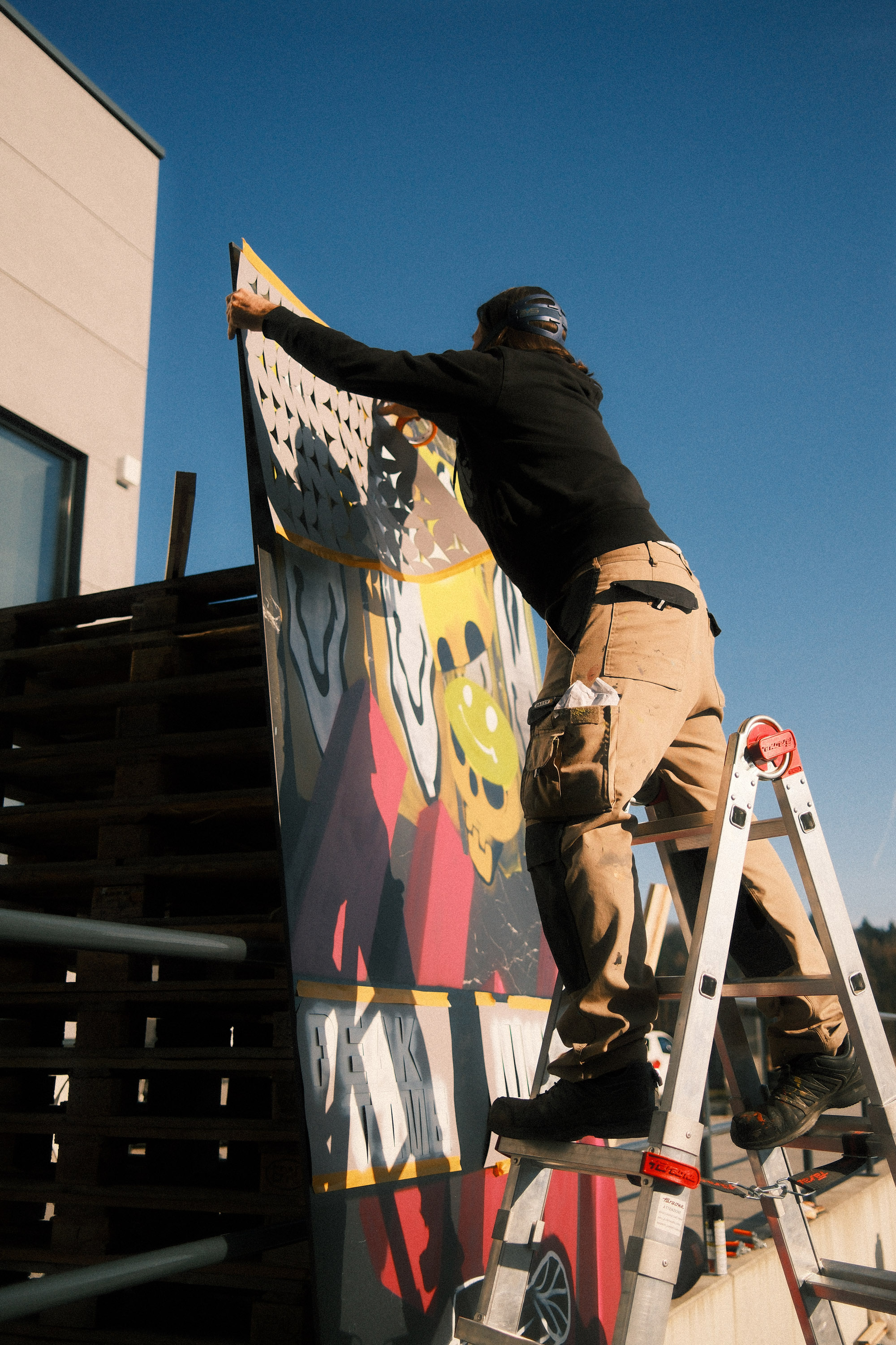 Loomit arbeitet auf der Leiter am grossformatigen Kunstwerk